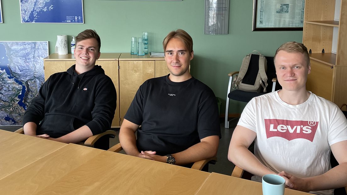 Tre studenter sitter langs et bord