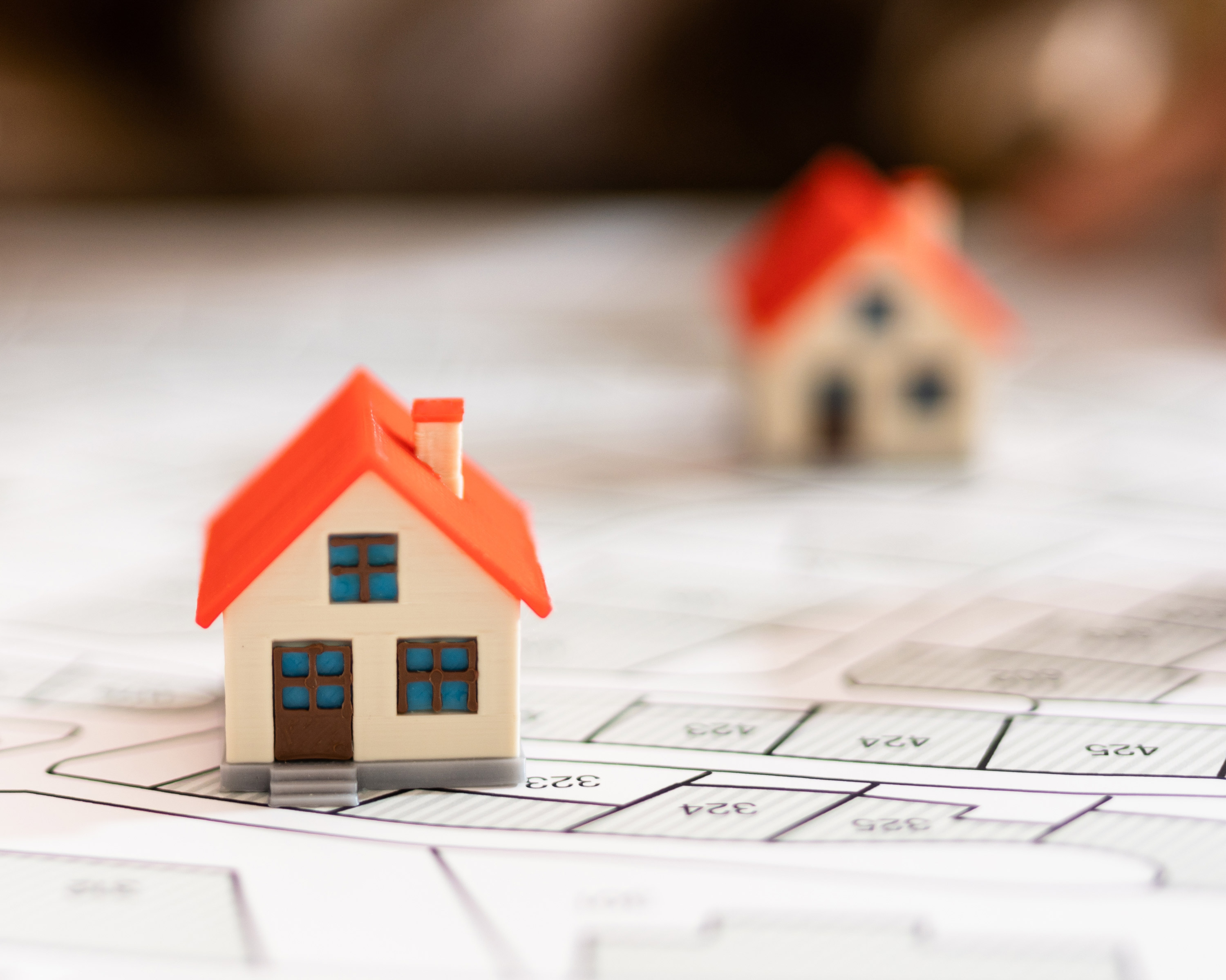 Miniatyrhus plassert oppå eiendomskart. Foto: Adobe Stock