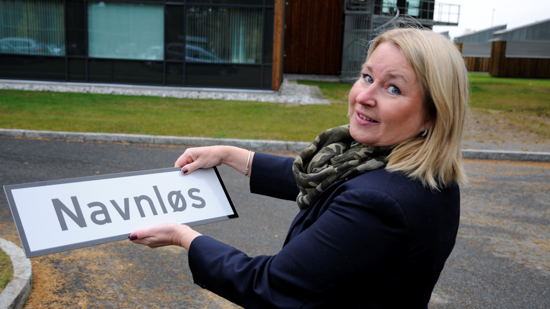 Kvinnelig ansatt i Kartverket med gatenavn-skilt med påskriften "Navnløs". Foto: Sveinung Engeland/ Kartverket