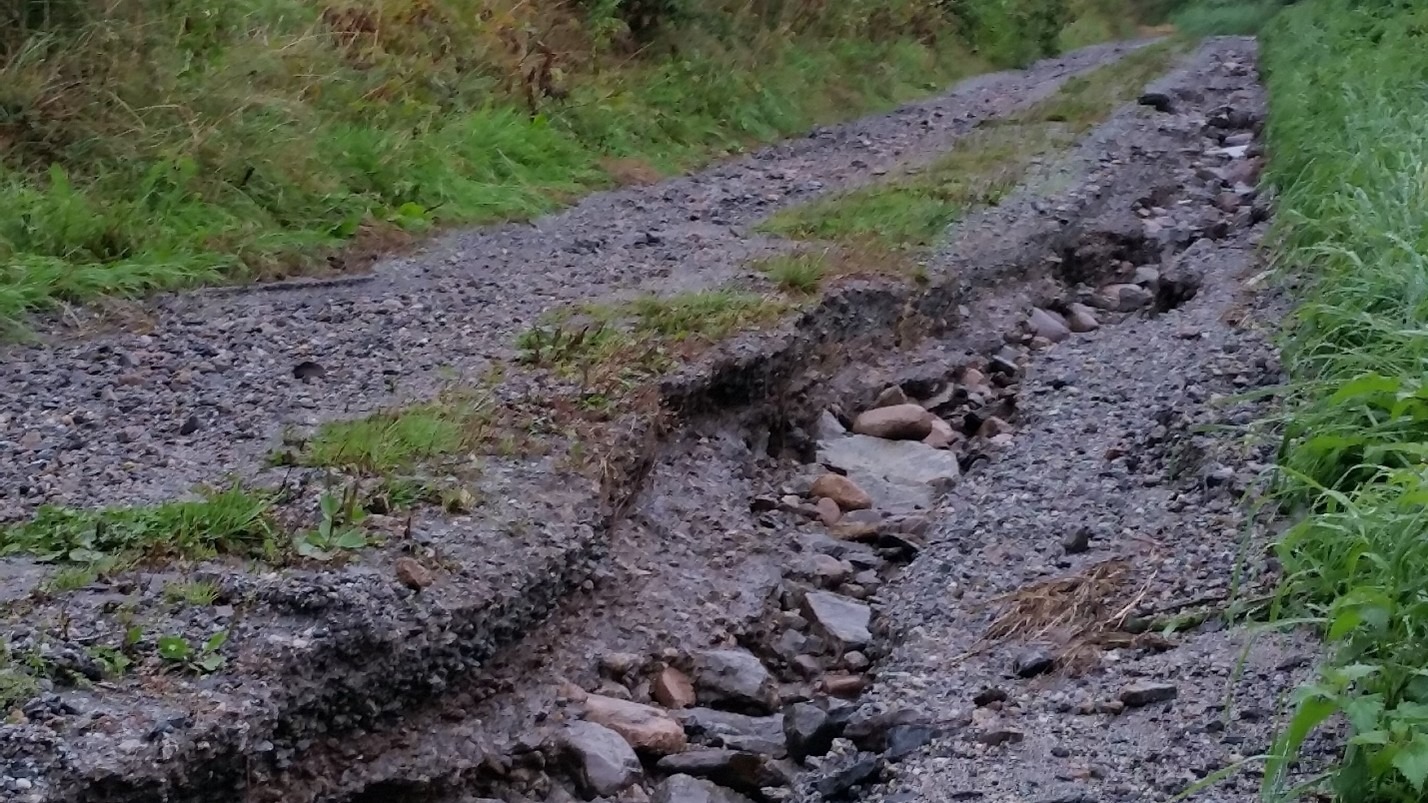 Grusvei er preget av skader fra vannerosjon.