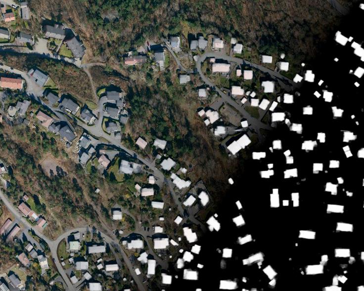 Flyfoto som viser store og små bygninger i terrenget. 