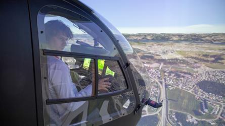 Person i helikopter-simulator med landskap rundt seg. Foto: Per Anders Bjørklund/ Kartverket