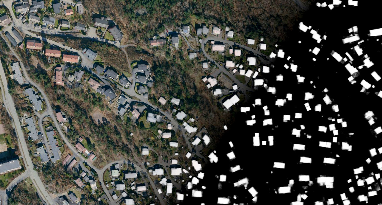 Flyfoto som viser store og små bygninger i terrenget. 
