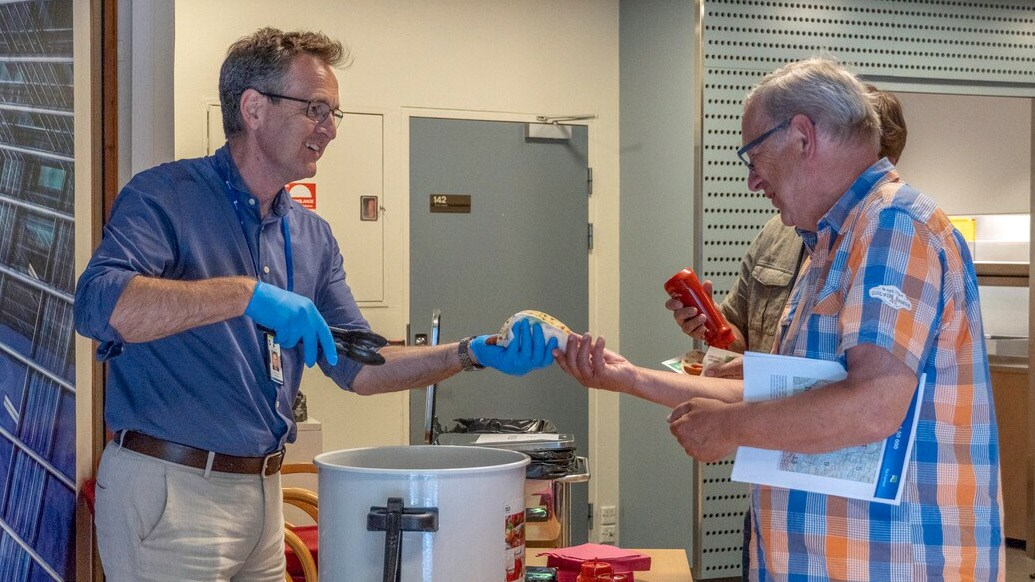 Knut Karper Bjørgaas serverer pølser til gjester hos Kartverket under åpen dag. Foto: Louise Larsen