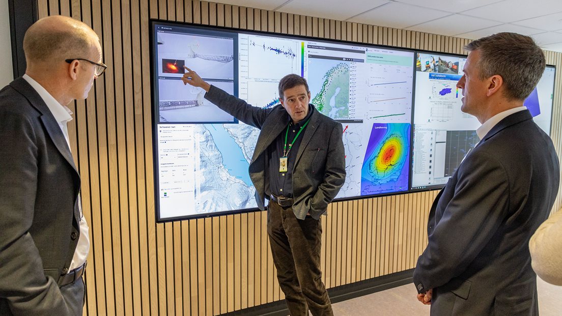 Geodesidirektør Per-Erik Opseth og statsråd Erling Sande foran store dataskjermer i Kartverkets kontrollsenter for geodesi. Foto: Åsgeir Størdal/ Kartverket