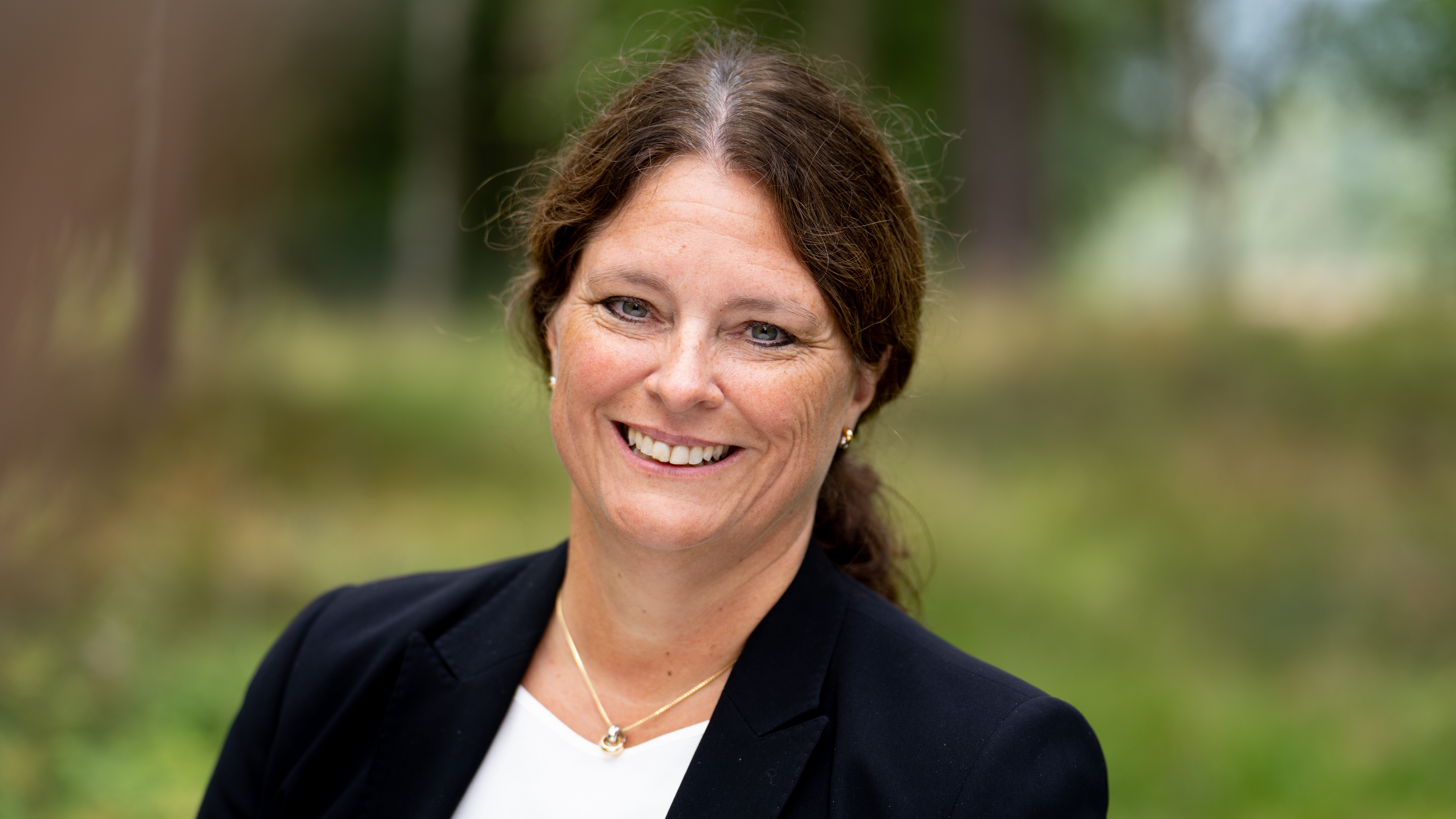 Hannah Cook smiler, grønn skog i bakgrunnen.