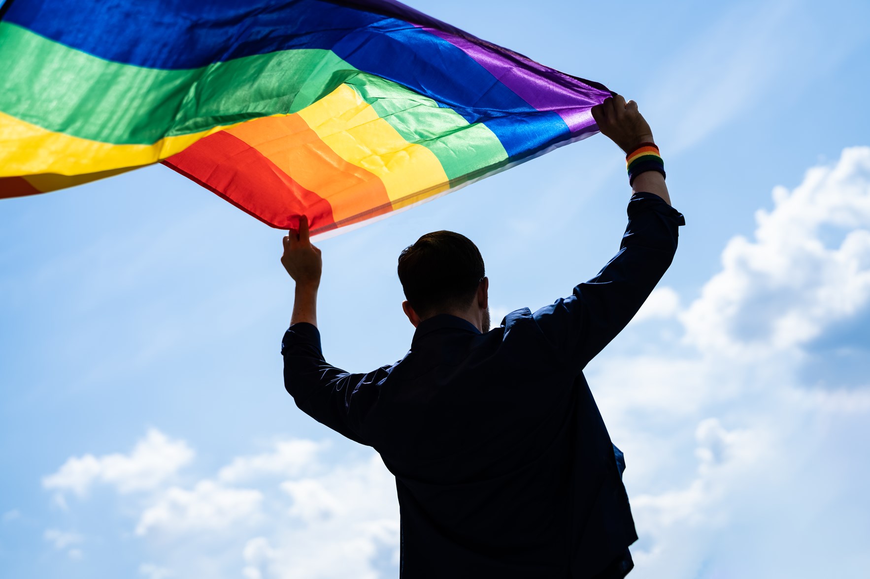 Pride-markering med mann som holder regnbueflagg. (foto: Andrey Popov/ Most Photos)