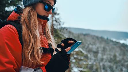 Kvinne på vintertur med Hvor?-appen oppe på telefonen. Foto: Adobe Stock