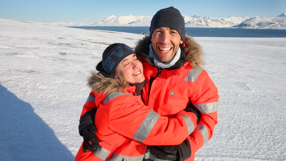 Susana Garcia Espada og Rubén Bolaño González holder rundt hverandre. Sola skinner over landskapet i Ny-Åleasund. Foto: Bjørn-Owe Holmberg