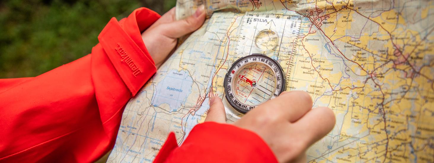 Kvinne bruker kompass og kart for å ta ut kursen
