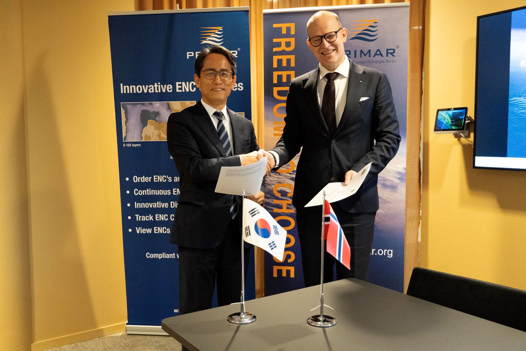 Kyusam Jung og Johnny Welle h&aring;ndhilser. Begge holder signerte versjoner av bilateral avtale mellom S&oslash;r-Korea og Norge.