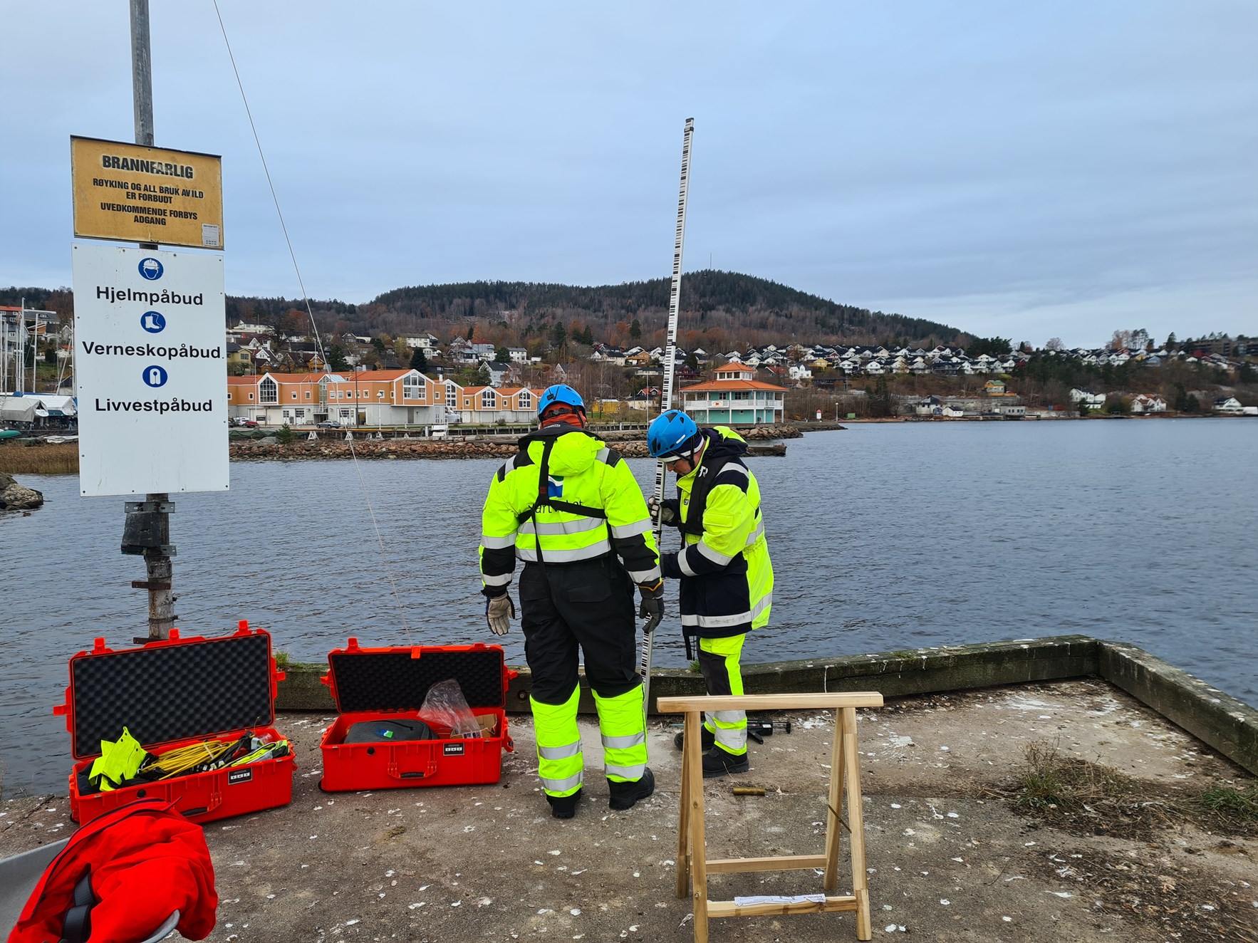 To arbeidere fra Kartverket monterer vannstandsmåler på brygge i Drammen