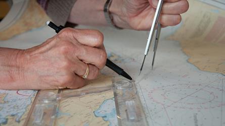 Hands plotting changes in a nautical chart. Photo.