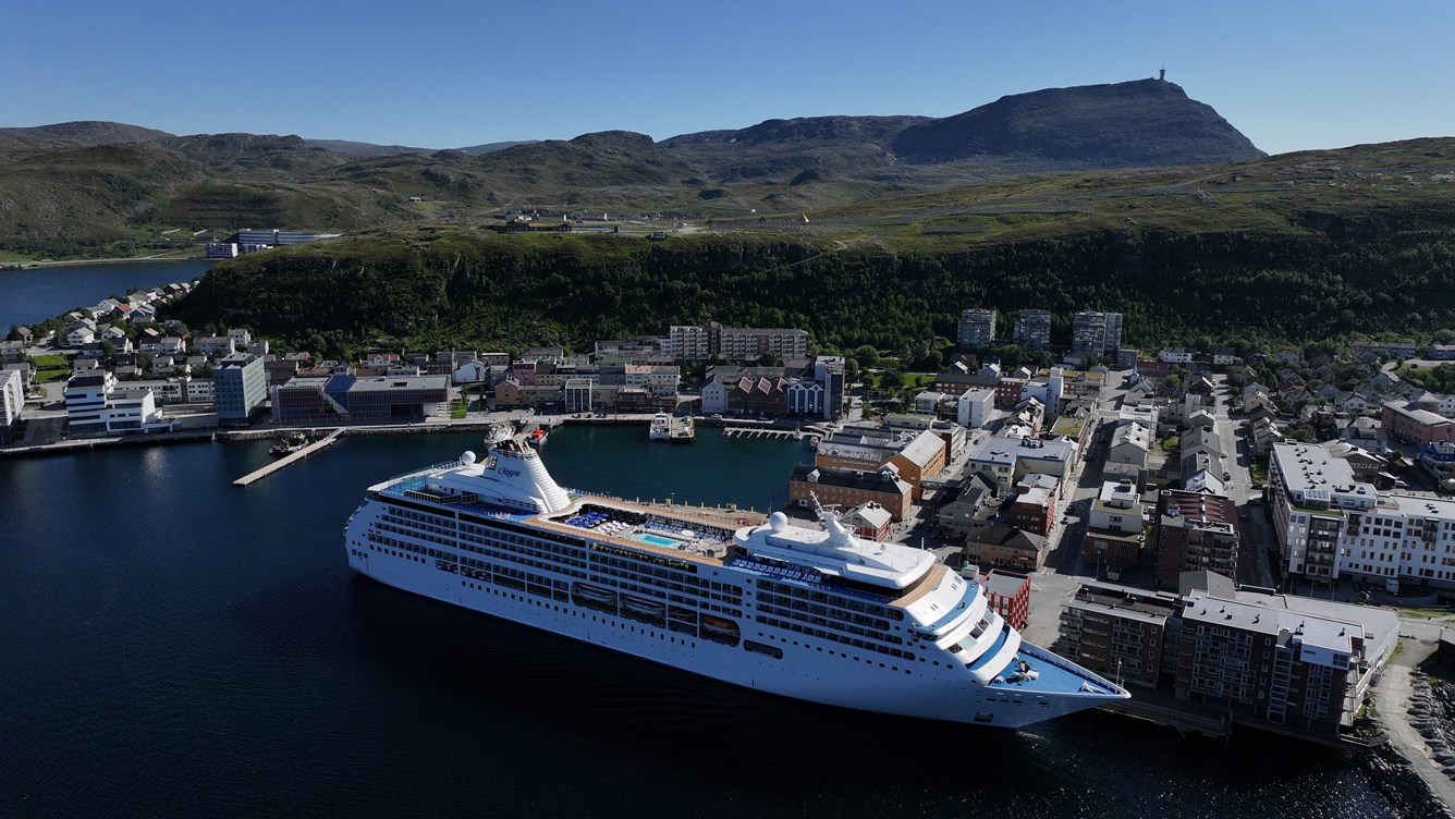 Oversiktsbilde av Hammerfest by hvor et større fartøy ligger fortøyd ved sentrumskaien.