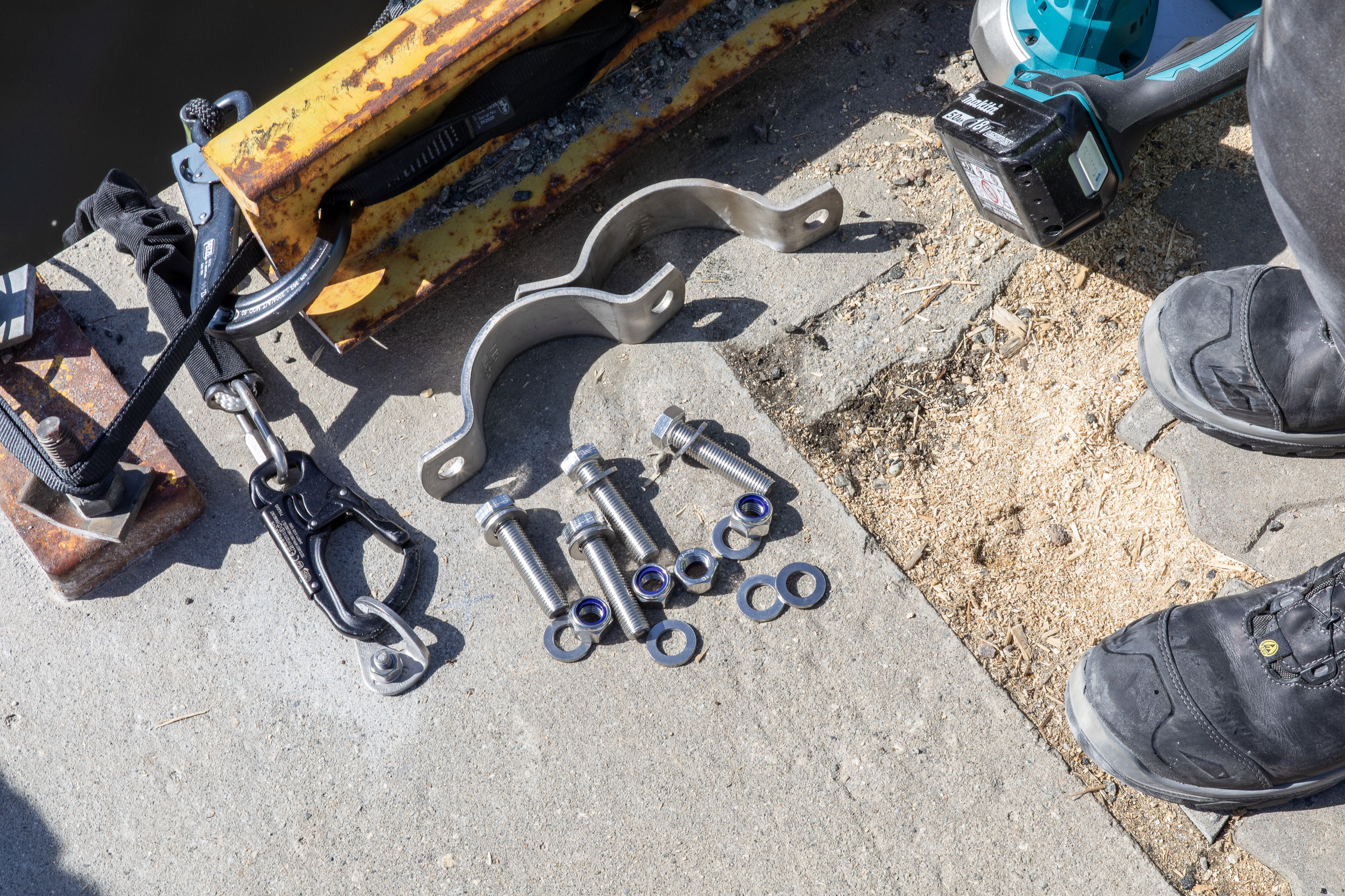 Klemmer og solide skruer p&aring; en betongkai foran skotuppene til en arbeider.